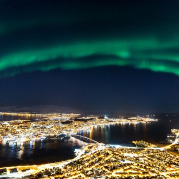 The northern lights over the city of Tromso, linking to www.bahighlife.com.