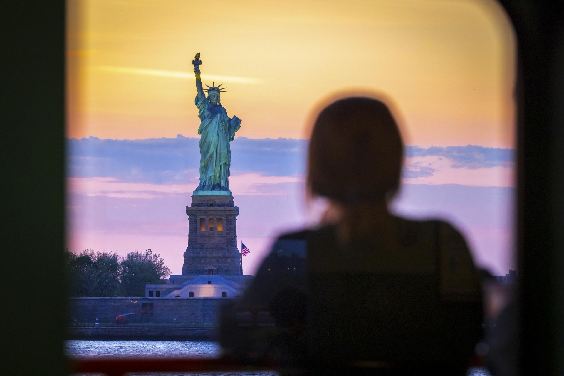 Adult admiring Statue of Liberty from the Staten Island Ferry in New York.