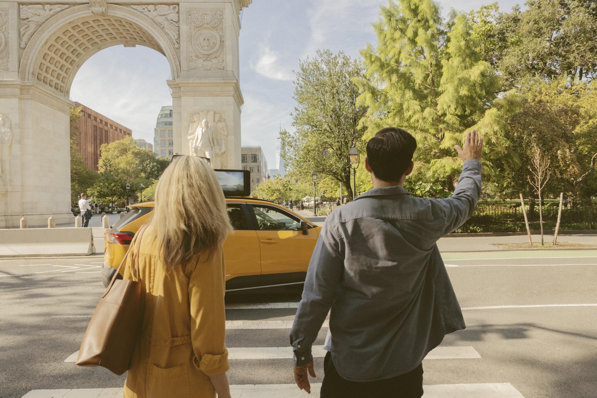 Two adults hailing a cab by Washington Square in New York City.