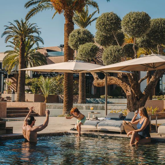 A family enjoying time in the swimming pool at Fairmont Royal Palm Marrakech, linking to BA High Life site.