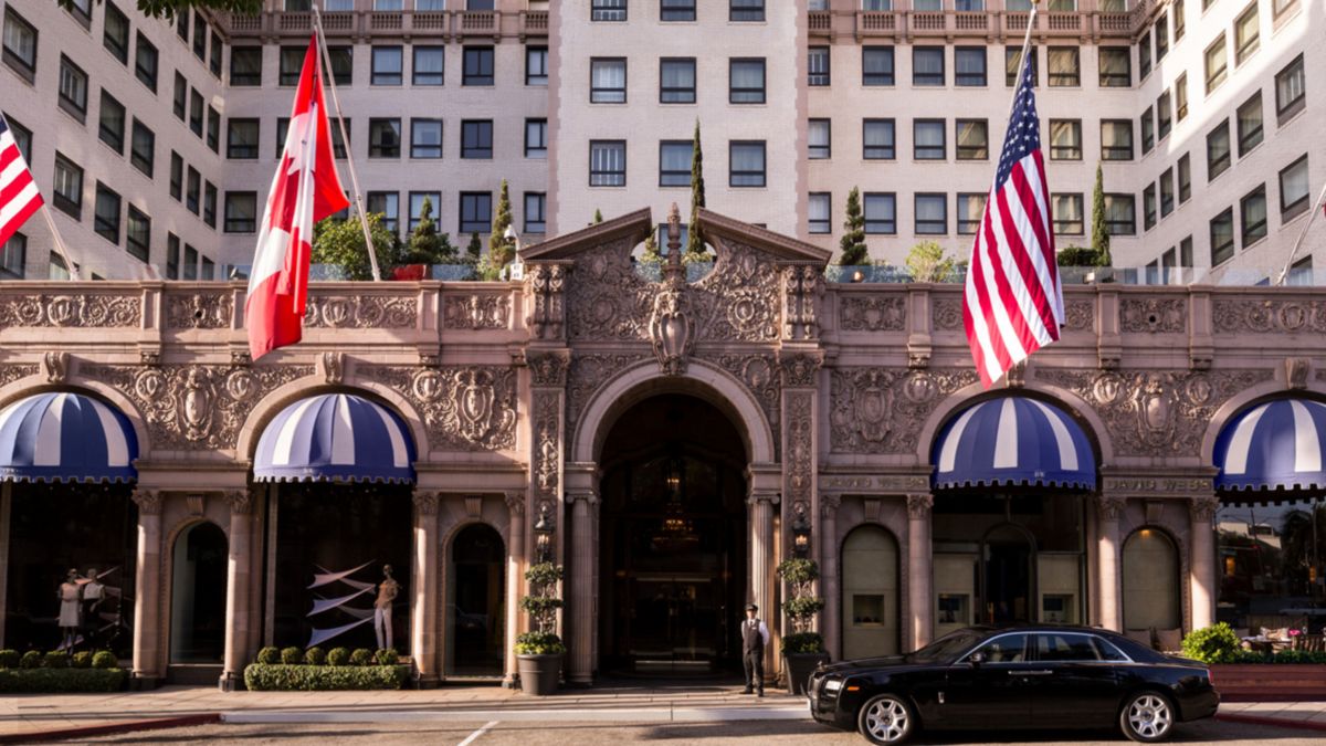 A concierge stands outside the impressive façade of the Beverly Wilshire hotel, links to BA High Life .com.