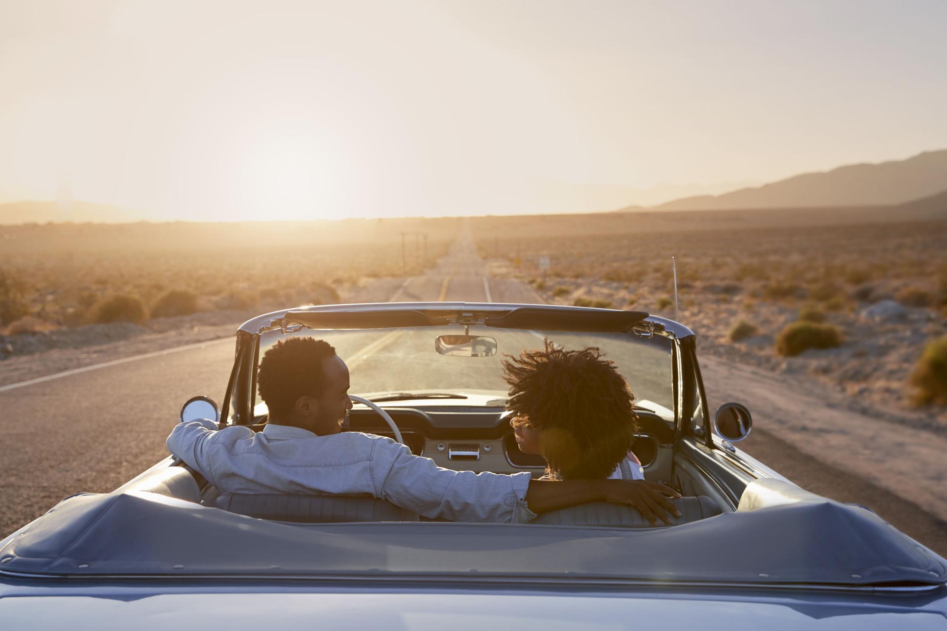 Adult couple driving in convertible sports car at sunset in Los Angeles.