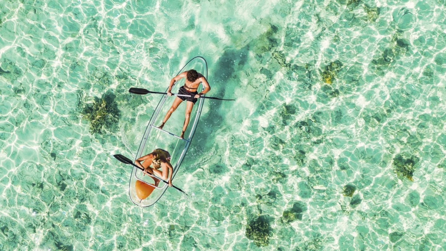 Couple paddling on glass bottom kayak in Indian Ocean, Maldives.