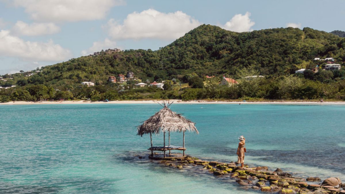 Rear view of woman standing on rock near Caribbean Sea in Antigua, linking to BA High Life site.