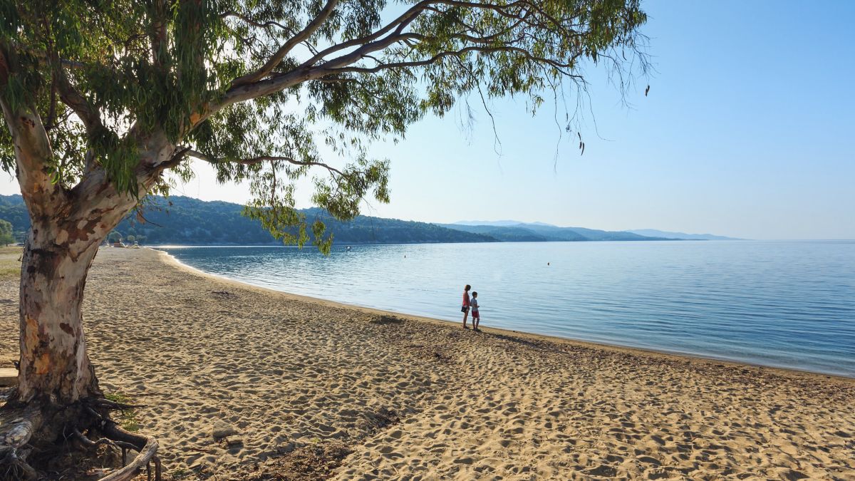 Family standing on Kastri beach in Halkidiki., linking to BA High Life site. 