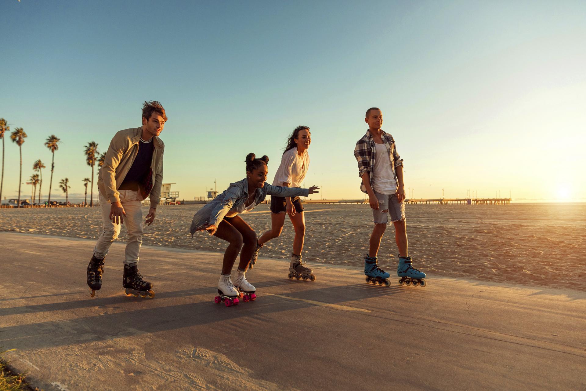 Friends roller skating on the boardwalk in Venice Beach, Santa Monica promenade in Los Angeles.