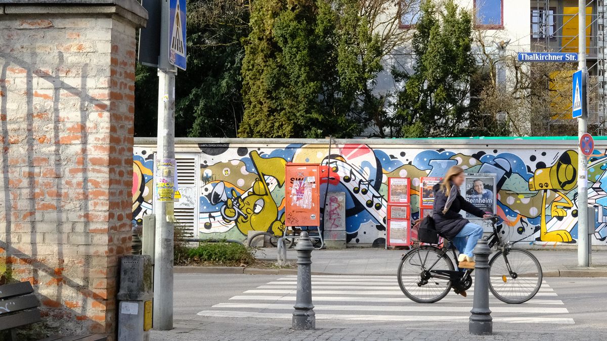 A visitor cycling past some colourful street art in Munich’s Glockenbach district.