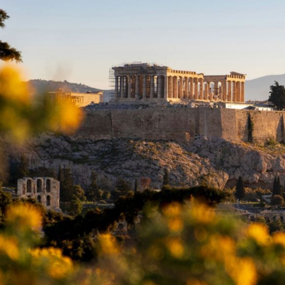 The Acropolis in the distance peeking through autumn foliage in Athens, linking to BA High Life site.