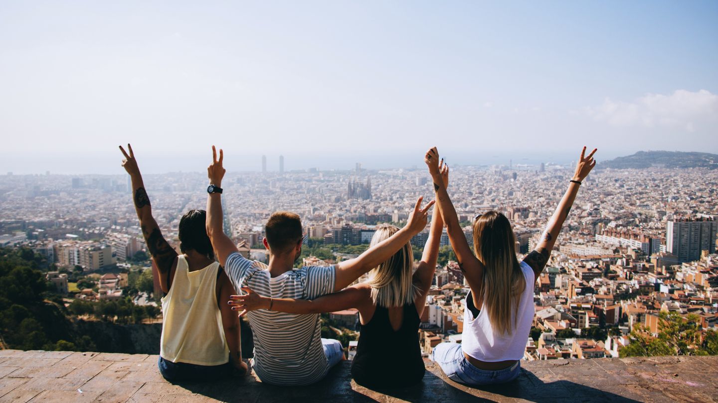Group of friends sitting in a lookout with the city ahead of them in Barcelona.