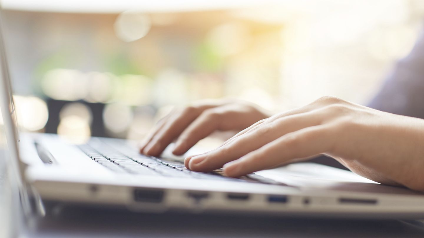 Hands typing on laptop keyboard.