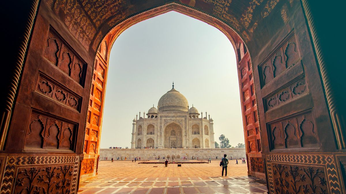 A visitor gazing up at the Taj Mahal on a bright day, linking to www.bahighlife.com.