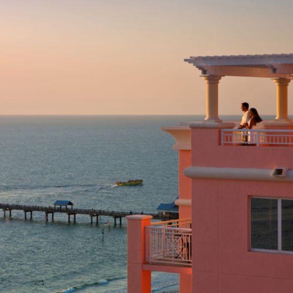 A couple look at the sunset from their terrace suite at Hyatt Regency Clearwater Beach Resort, linking to BA High Life site.​