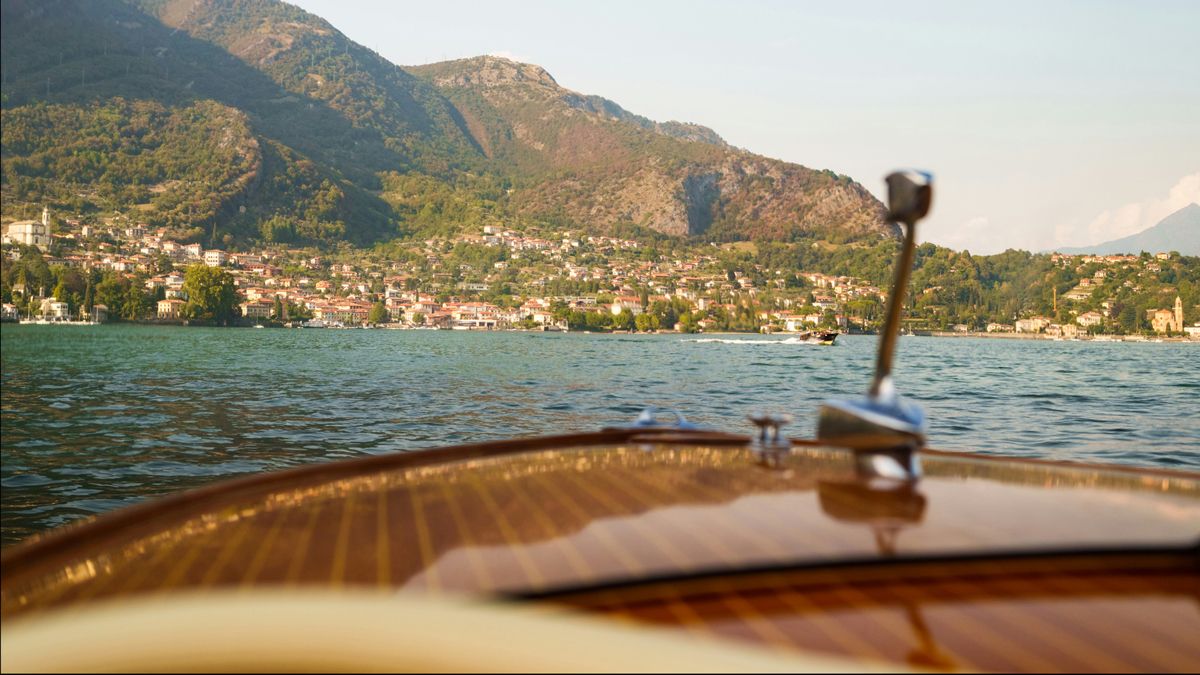 Looking out from the front of a boat towards the banks of Lake Como, linking to BA High Life website.