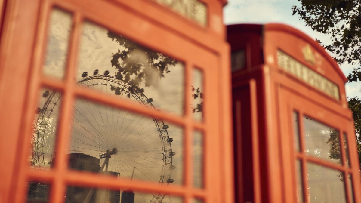 Reflection of the London Eye in the window of a red phone box in London.​