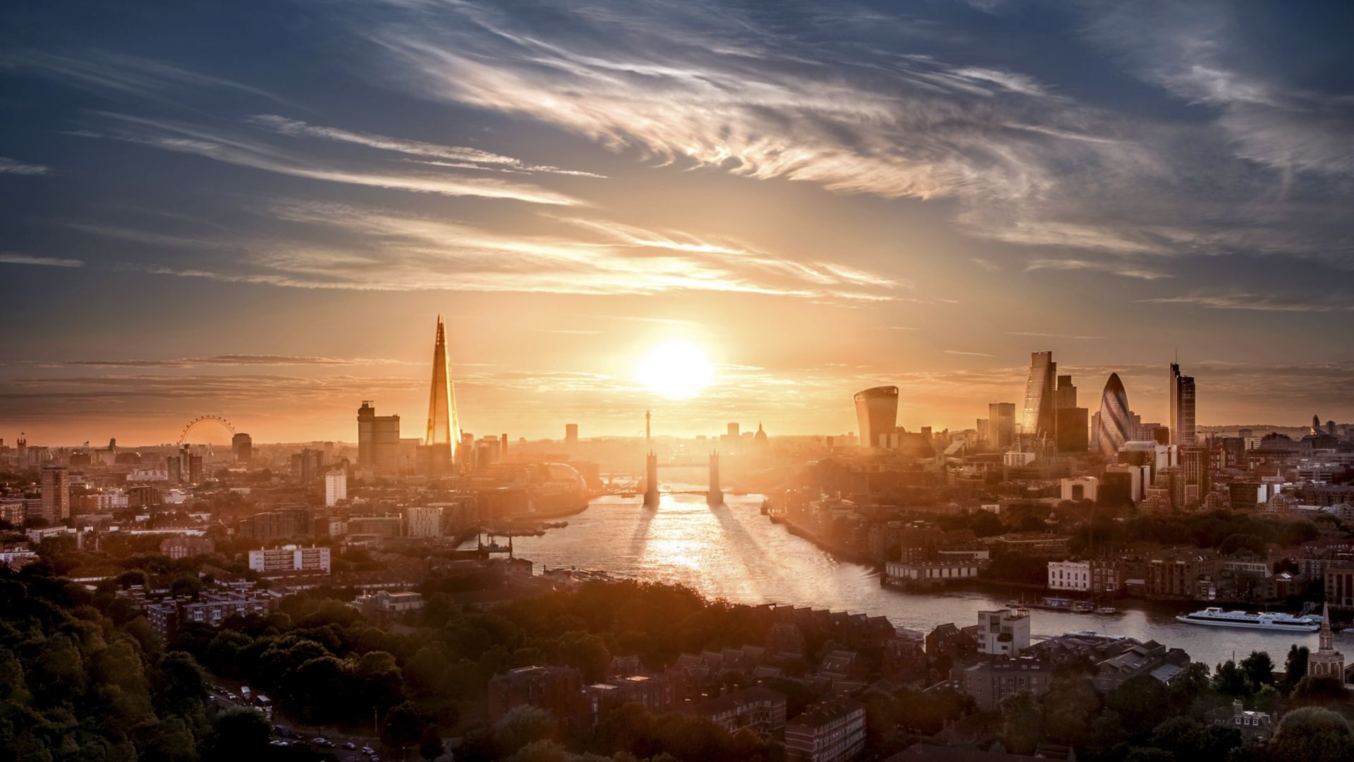 A view of Tower Bridge and the London skyline at sunset.