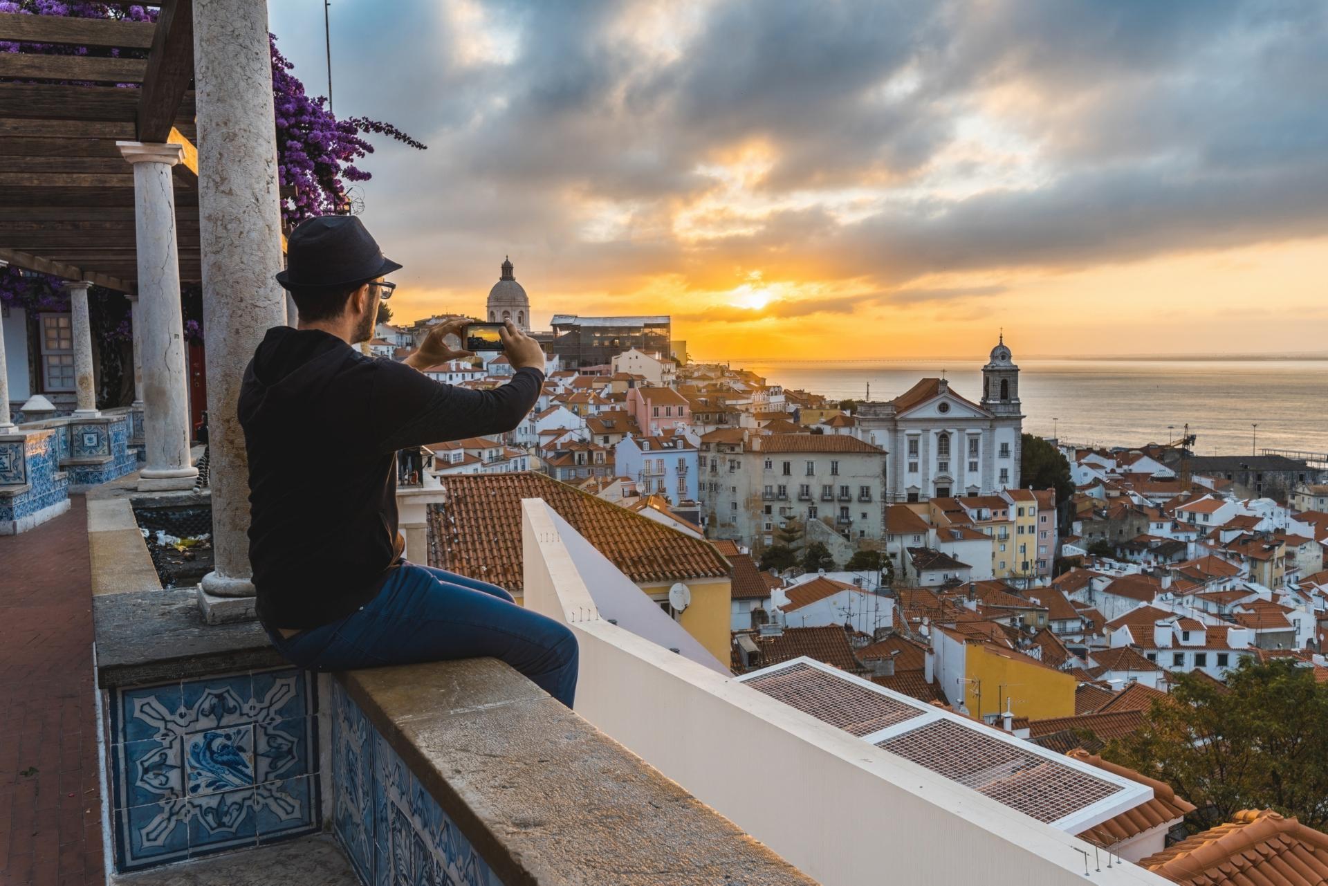 Tourist photographing with smartphone at sunrise in Lisbon.