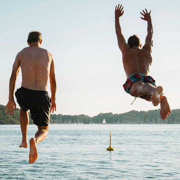 Two men jumping into Sørenga Seawater Pool in Oslo, linking to BA High Life site.