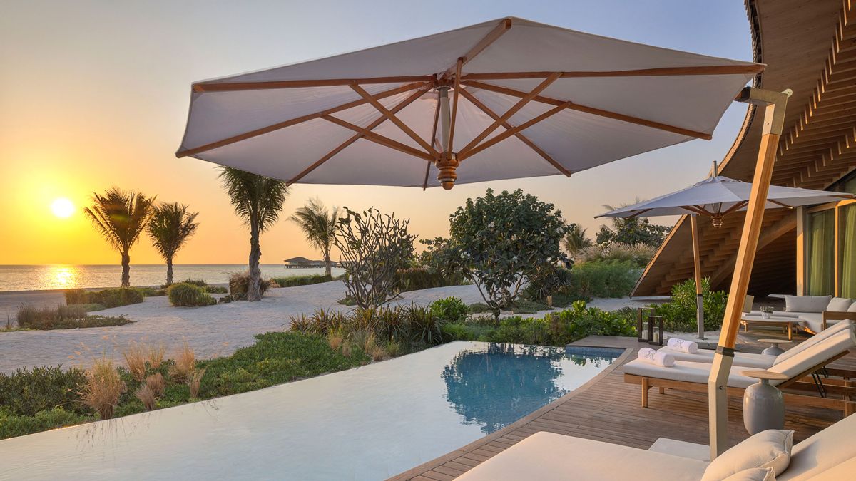 Loungers at The St Regis Red Sea, Saudi Arabia, looking out across a private infinity pool and the beach beyond at sunset, links to BA High Life.com.