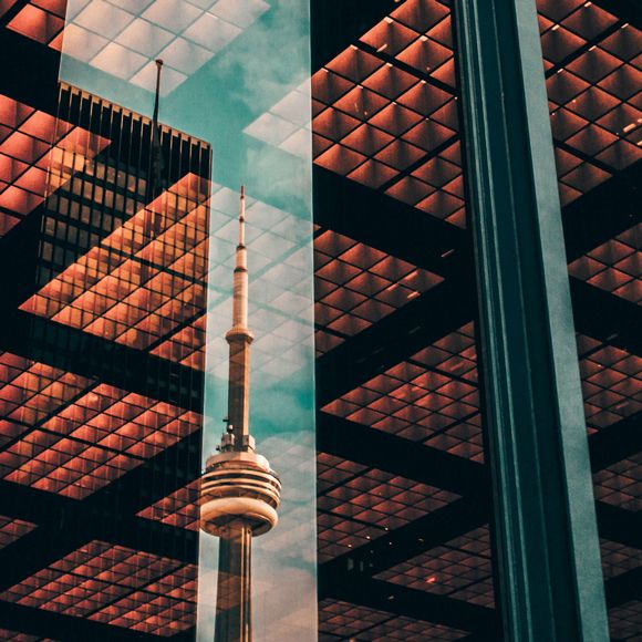 Toronto’s CN Tower reflected in a window in the city centre, linking to BA High Life website.