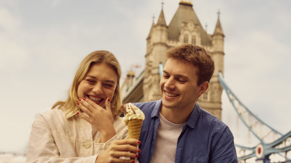 Two adults sitting Tower Bridge in London.