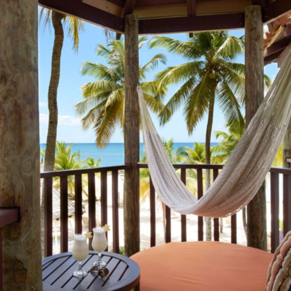 Balcony of a beachfront suite at a hotel in St Lucia, with palm trees and the sea in the distance, linking to BA High Life site.